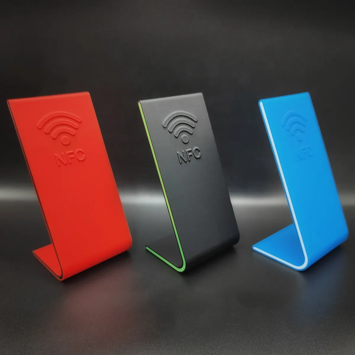 Kırmızı, koyu gri ve mavi renklerde, kabartma NFC işaretli üç masa standı